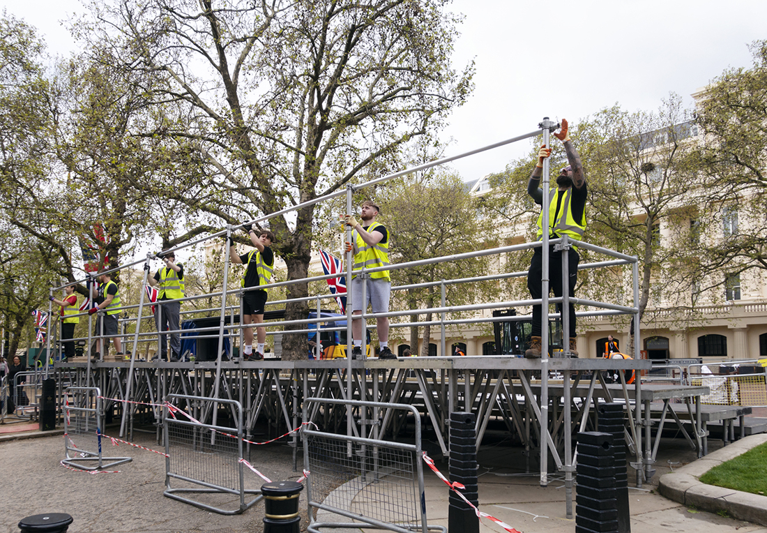A line of men who are dismantling a viewing stand which had been used for the Coronation of King Charles III the previous day. A major clean-up was underway in The Mall and nearby streets.